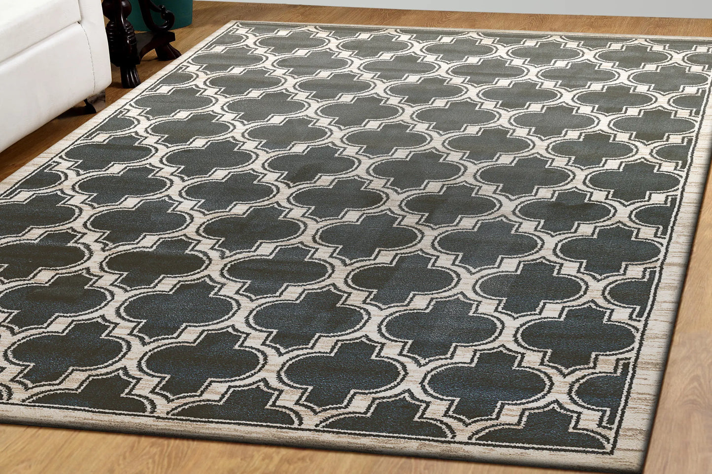 A rectangular traditional wool rug with a geometric pattern in beige and black colors on a wooden floor.