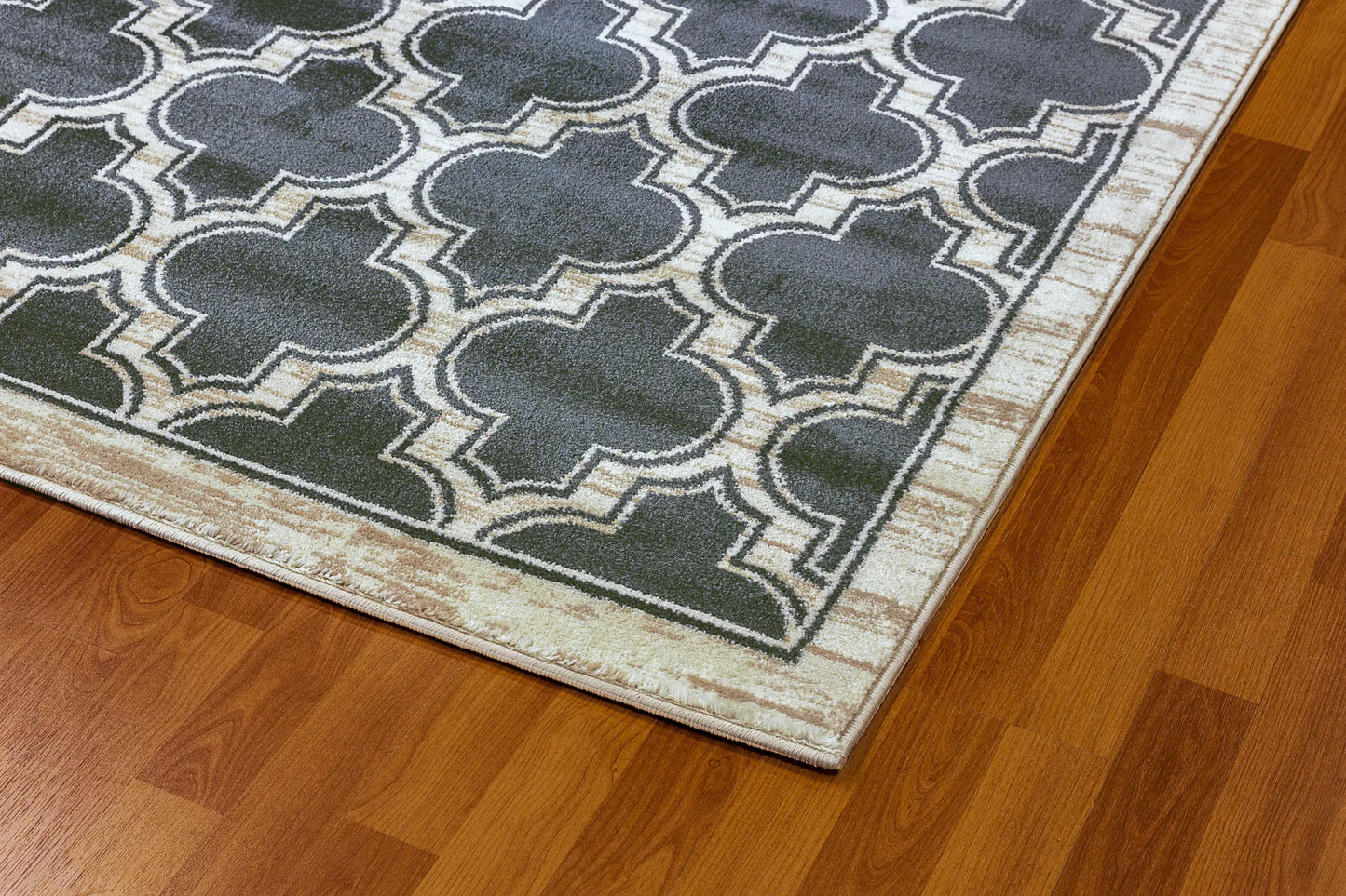 The closeup edge of a rectangular traditional wool rug with a geometric pattern in beige and black colors.